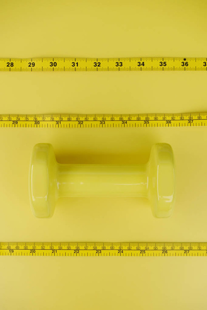 Fitness concept dumbbell and measuring tape for background - Photo, Image