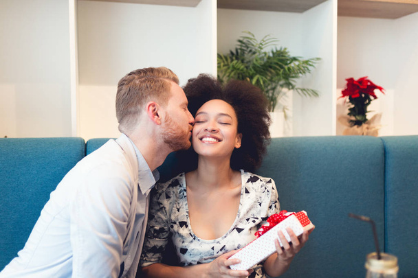 Pareja multirracial saliendo. Hombre pelirrojo guapo con hermosa mujer afroamericana teniendo vacaciones en la cafetería
 - Foto, imagen