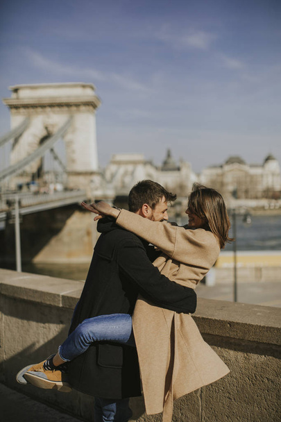 ブダペスト、ハンガリーの壮大な景色の背景を抱いて愛の若い幸せな魅力的なカップル - 写真・画像