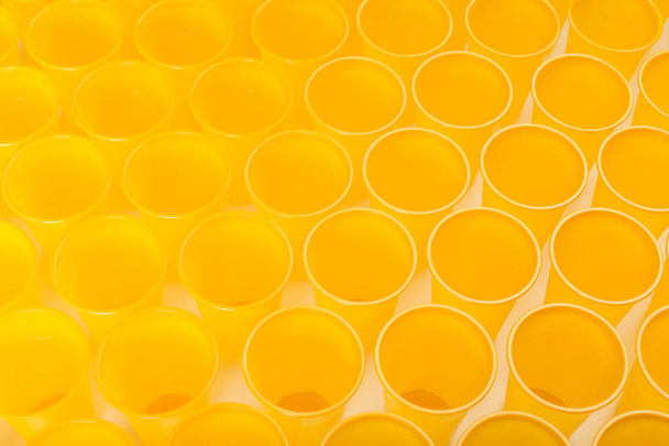 yellow disposable plastic glasses on white background - 写真・画像