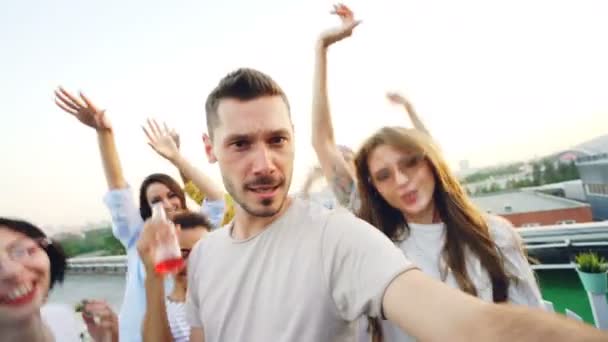 Точка зору знімок бородатого хлопця популярний блогер записує відео для інтернет-блогу на сучасній вечірці під відкритим небом з друзями танцює і сміється
. - Кадри, відео