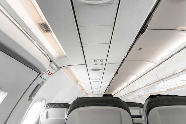 Emergency exit on an aircraft, view from inside of the plane. Empty airplane seats in the cabin. Modern Transportation concept. Aircraft long-distance international flight - Photo, Image