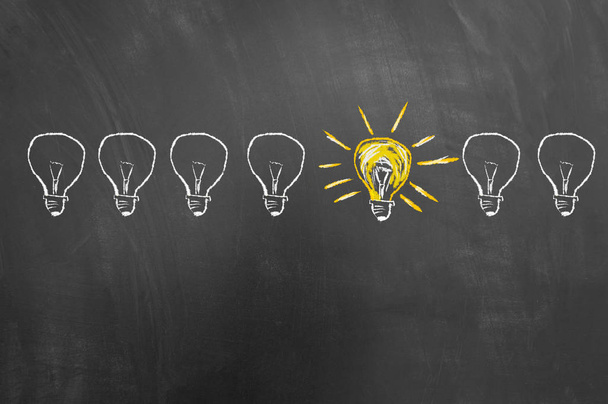 Smart creative idea concept drawing on blackboard or chalkboard with bright yellow light bulb sketch - Foto, imagen