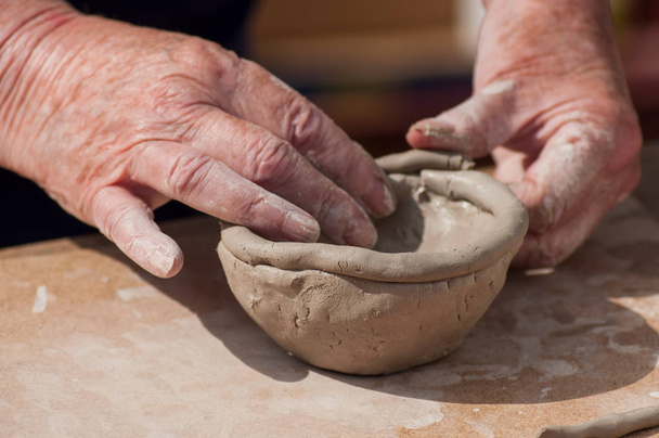 closeup of hands of old woman making clay pottery bowl in outdoor  - Valokuva, kuva