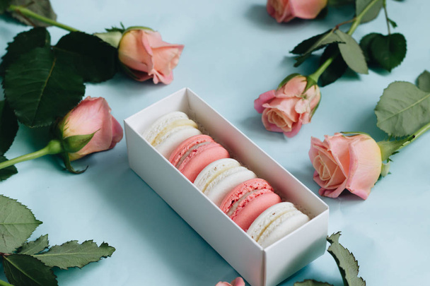 composition of delicious macaroons and pink roses on blue table - Fotografie, Obrázek