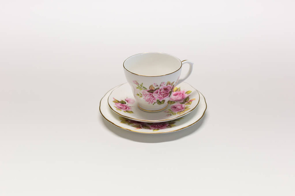 Πορσελάνης Κίνα τσάι Κύπελλο σετ με ένα ροζ τριαντάφυλλο σχεδιασμό σε μια λευκή επιφάνεια - Φωτογραφία, εικόνα