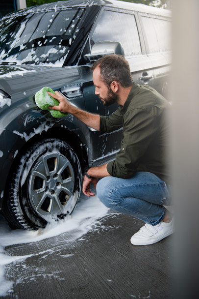 side view of handsome man cleaning car at car wash with rag - Φωτογραφία, εικόνα