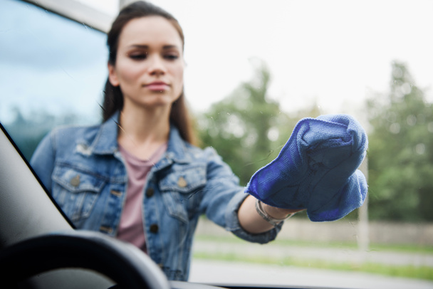 jeune femme attrayante nettoyage vitre de voiture avant avec chiffon
 - Photo, image