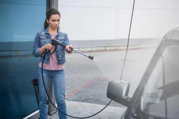 donna attraente pulizia auto a lavaggio auto con getto d'acqua ad alta pressione
 - Foto, immagini