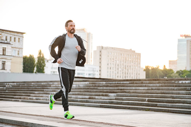 Motivated sportsman running outdoors on a city street - Fotografie, Obrázek
