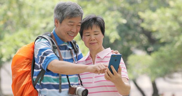 Старшие старые друзья общаются друг с другом в открытом парке, показывая фото на мобильном телефоне другим
 - Фото, изображение