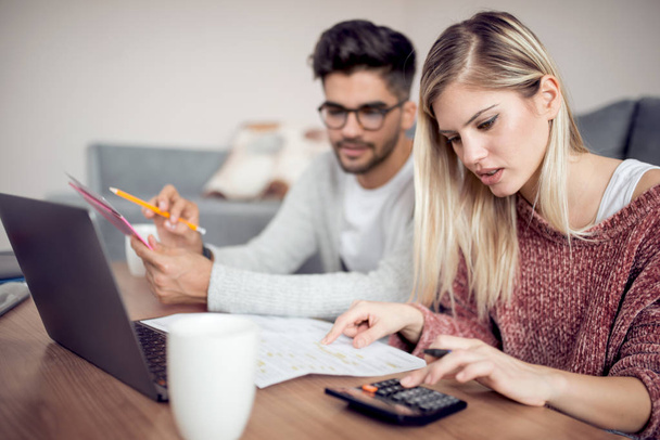 Young couple using laptop and analyzing finances with documents - Photo, Image