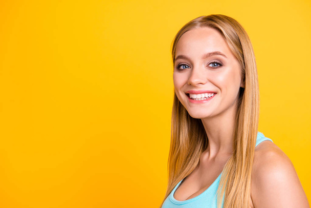 Closeup portrait of pretty beautiful blond girl, isolated on yellow background with copy space for text. Cute female model with big smile half a turn and looking at camera - 写真・画像