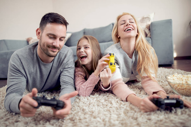 Ευτυχισμένη οικογένεια παίζει video game στο πάτωμα στο σπίτι. - Φωτογραφία, εικόνα