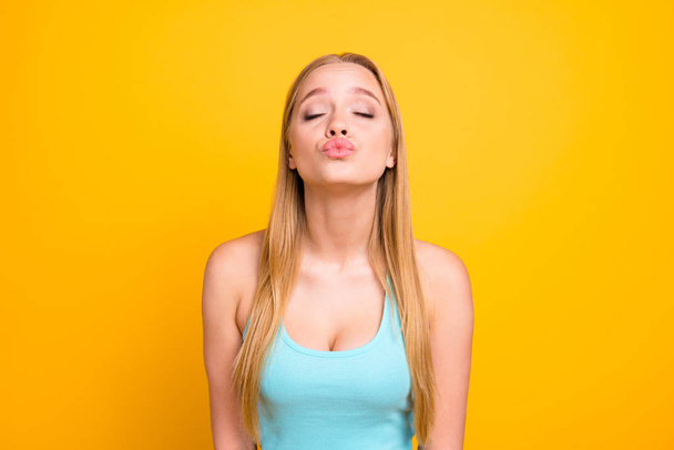 Very beautiful and gentle blonde girl with long straight hair closed her eyes in anticipation of a kiss isolated on yellow background - Zdjęcie, obraz