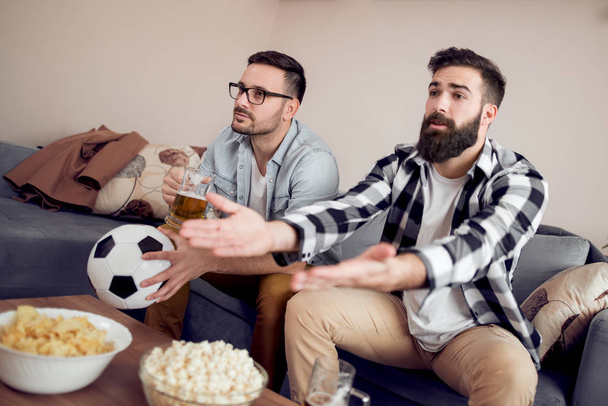 zwei junge Fußballfans, die zu Hause im Fernsehen Fußball schauen - Foto, Bild