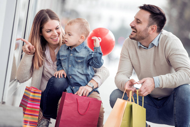 市内に小さな子供とショッピングバッグを持つ幸せな家族. - 写真・画像