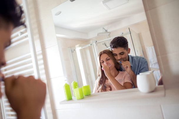 Young couple brushing teeth together at home in the bathroom. - Photo, Image