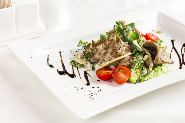 Salade chaude avec viande, champignons, tomates cerises, pignons et herbes
 - Photo, image