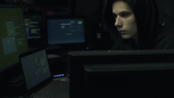 Mladý hacker s kapucí spojení online se svými počítači, hacking a cyber zločin koncepce - Záběry, video