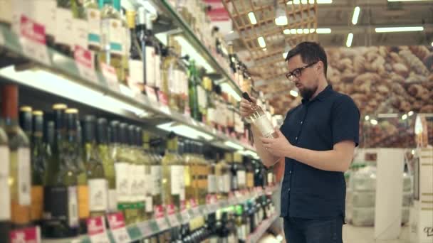 Erkek ziyaretçi bir şarap şişesi üzerinde yazıtlar okuma beyaz şarap seçmektir - Video, Çekim
