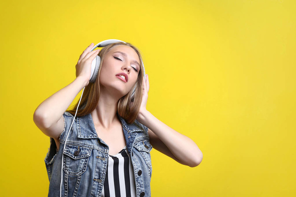 young woman with headphones on yellow background - Фото, зображення