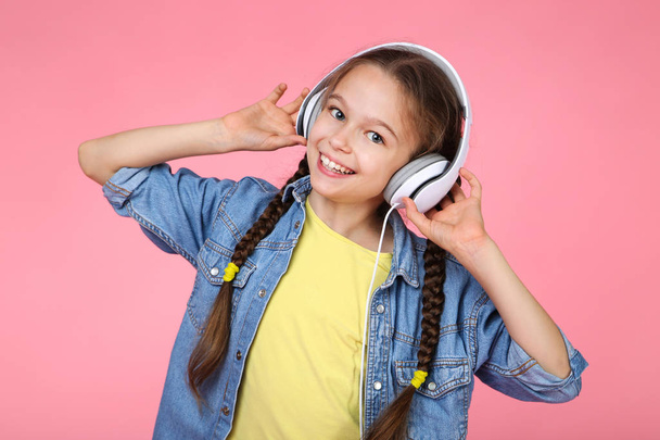 Young girl with headphones on pink background - Фото, изображение