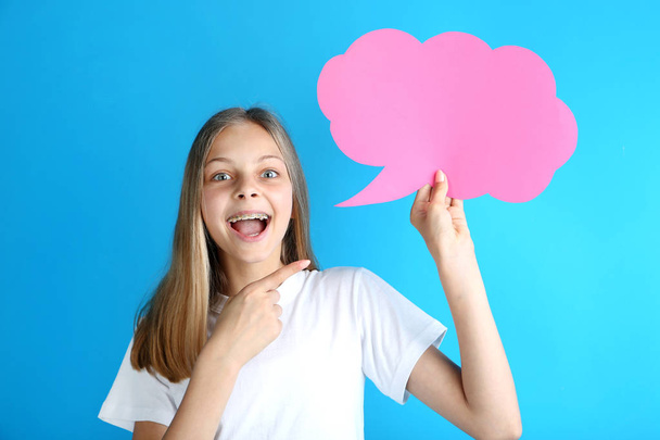 Young girl holding pink speech bubble on blue background - Φωτογραφία, εικόνα