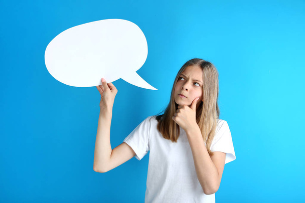 Young girl holding white speech bubble on blue background - Foto, Bild