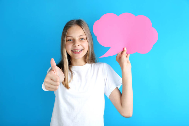Young girl holding pink speech bubble on blue background - Фото, зображення