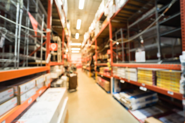 Blurred large hardware store. Defocused interior home improvement retailer with racks of flooring tools and material as wire and metal shelving, moulding, wood trim, laminate floor up to ceiling. - Photo, Image