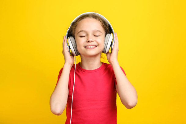 Young girl with headphones on yellow background - Φωτογραφία, εικόνα
