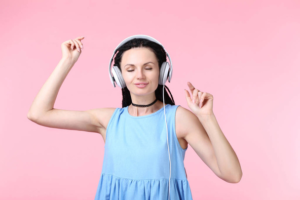 Young woman with headphones on pink background - Φωτογραφία, εικόνα