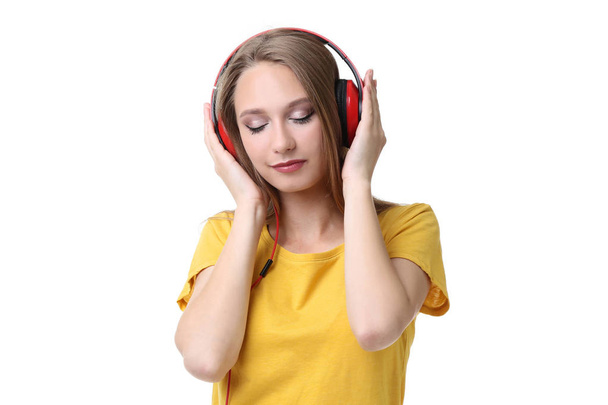 Young woman with headphones on white background - Fotó, kép