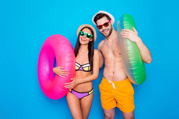 Delight pleasure leisure daydream concept. Portrait of funky positive couple with colorful rubber rings enjoying rest isolated on bright blue background - Foto, Imagem