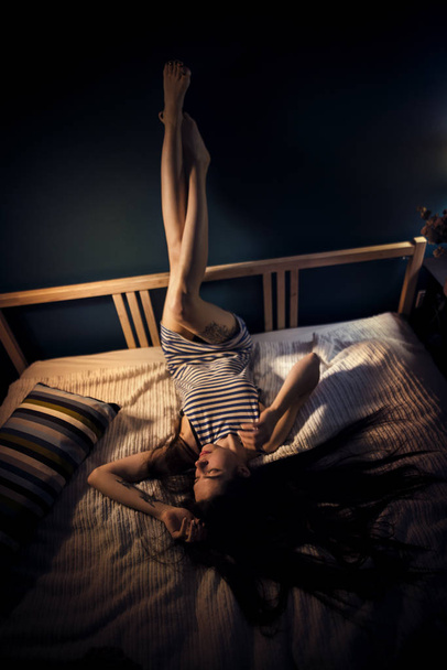 Young attractive woman on a bed at night room - 写真・画像