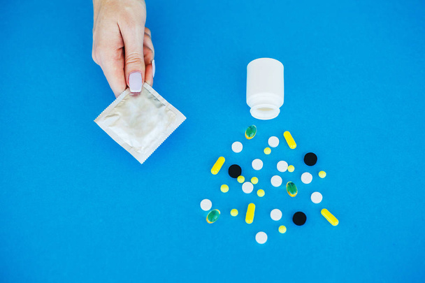 Pillole anticoncezionali e preservativo scartato. Pillole colorate e capsula su sfondo blu. Tema della farmacia, pillole della capsula con antibiotico della medicina nei pacchetti
. - Foto, immagini