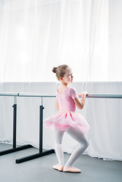 back view of adorable little ballerina exercising in ballet school - Foto, afbeelding