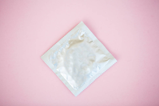 Contraception. Birth Control Pills and an unwrapped Condom. Colored Pills And Capsule On Pink Background. Pharmacy Theme, Capsule Pills With Medicine Antibiotic in Packages. - Photo, Image