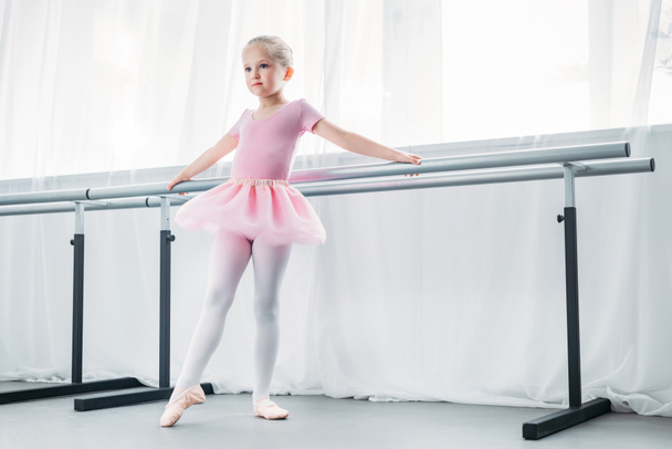 adorable little ballerina in pink tutu practicing in ballet studio - Fotó, kép