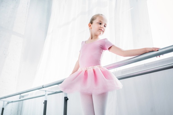visão de baixo ângulo da criança adorável em tutu rosa praticando no estúdio de balé
  - Foto, Imagem