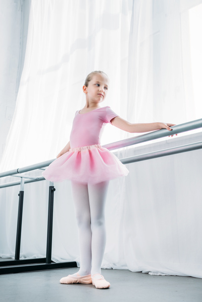 low angle view of adorable little ballerina in pink tutu practicing in ballet studio  - Photo, Image
