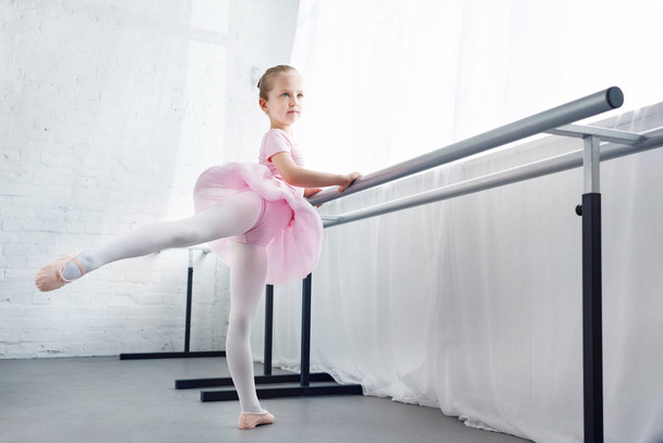 adorable pequeña bailarina en tutú rosa practicando en estudio de ballet
  - Foto, Imagen