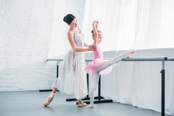 young ballet teacher exercising with cute little student in ballet studio  - Zdjęcie, obraz