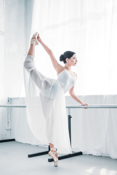 side view of graceful flexible young ballerina practicing ballet in studio  - 写真・画像