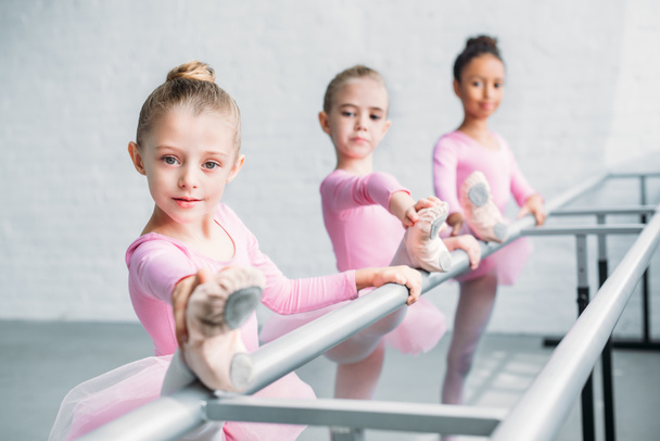 prachtige kinderen camera kijken tijdens het uitrekken in balletschool - Foto, afbeelding