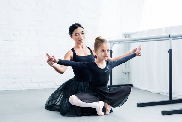 Junge Ballettlehrerin bildet süßes flexibles Kind in Ballettschule aus - Foto, Bild