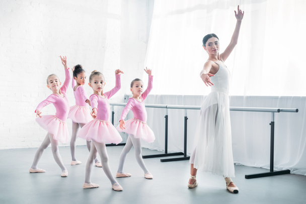 joven profesor practicando ballet con adorables niños en faldas de tutú rosa
 - Foto, imagen