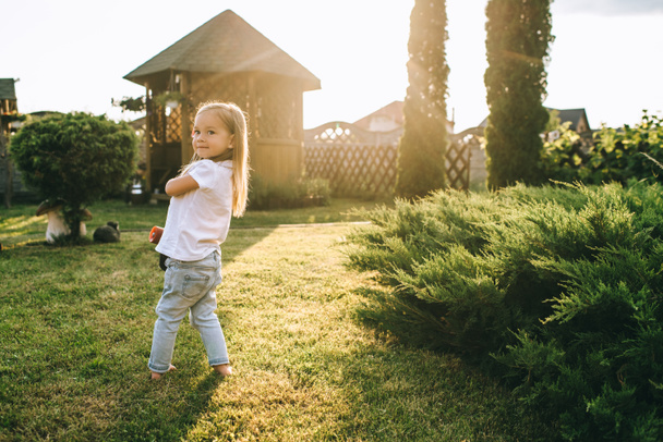 side view of adorable little child with skateboard in hands on yard - Foto, Bild