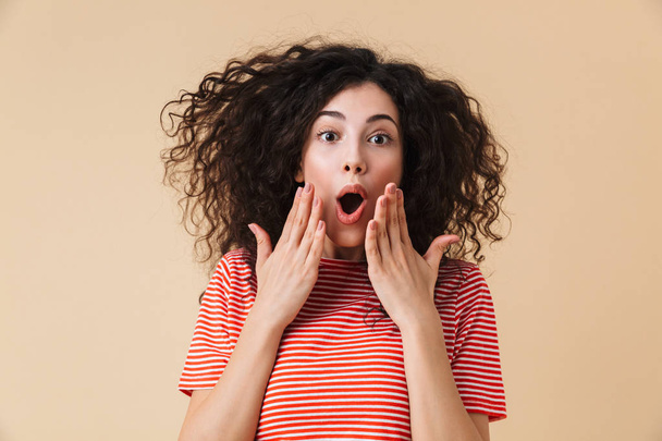 Photo of excited shocked young woman isolated over beige wall background looking camera. - Foto, afbeelding
